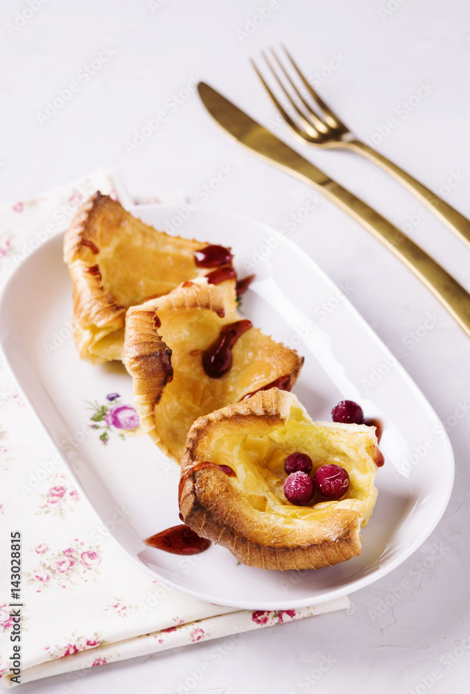 Fresh homemade crunchy popovers on a white plate on a grey concrete background. Selective focus Fresh homemade crunchy popovers on a white plate on a grey concrete background. Selective focus