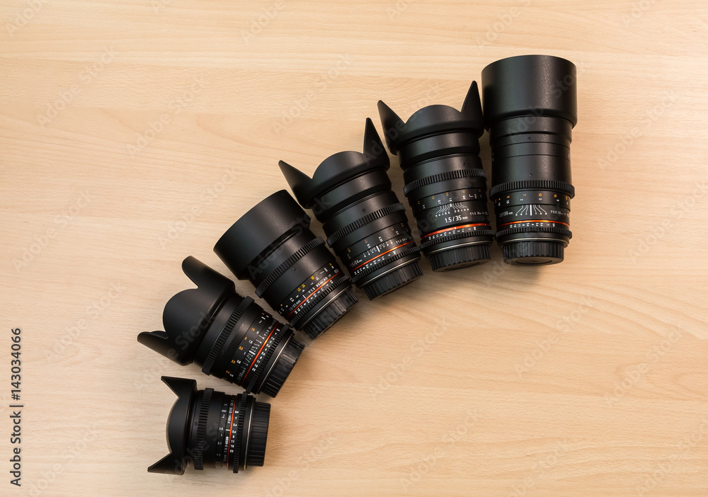 Six lenses with different focal lengths lie on a wooden surface. Filming using DSLR cameras. Equipment for movies.