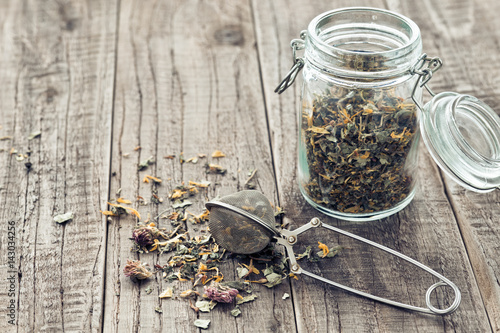 Teeblätter mit einem Teesieb und einem Glas auf einem Holzbrett