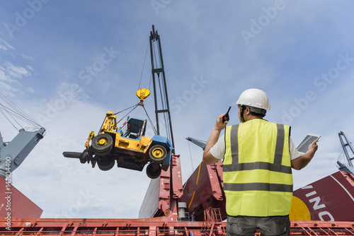 forman control loading the cargo by walkie talkie raio on the heavy crane services in background © ID_Anuphon