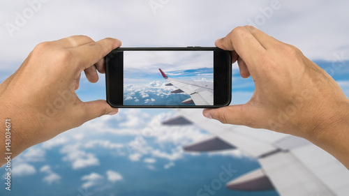 Phone on hand with blur View of airplane window with sky background travel concept.