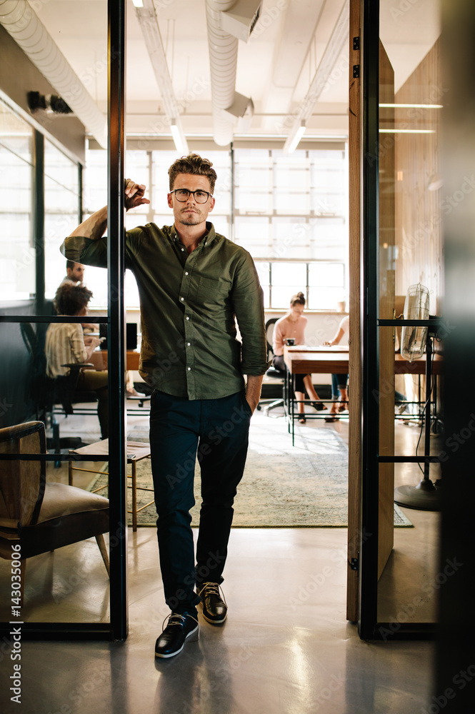 Young man standing in doorway at startup office Young man standing in doorway at startup office