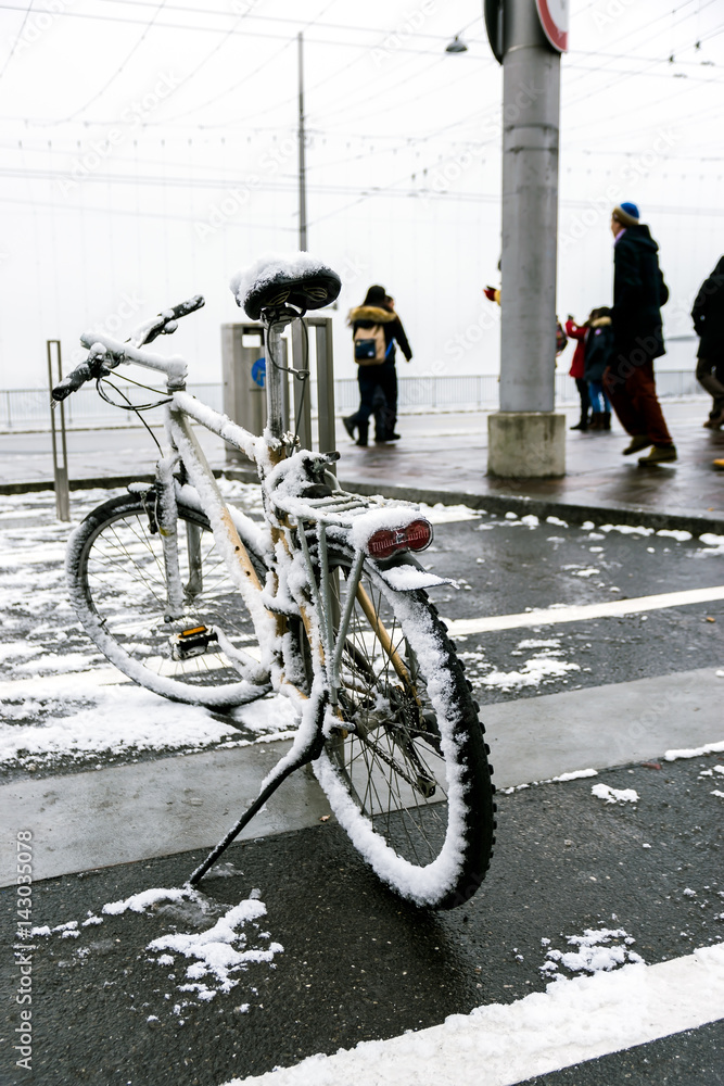 The bicycle parked on the road is covered with snow in winter in Switzerland.
