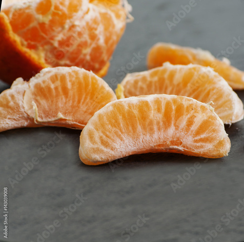 Ripe Mandarin fruit peeled open and place on old rustic look timber