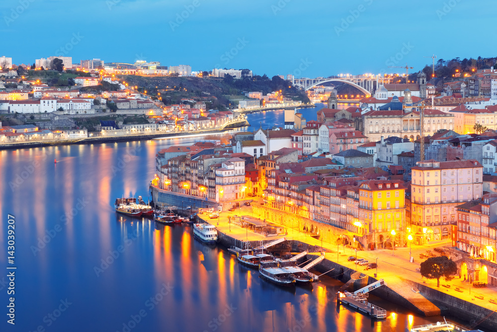 Picturesque aerial view of Old town of Porto, Ribeira and bridge with mirror reflections in the Douro River during morning blue hour, Portugal