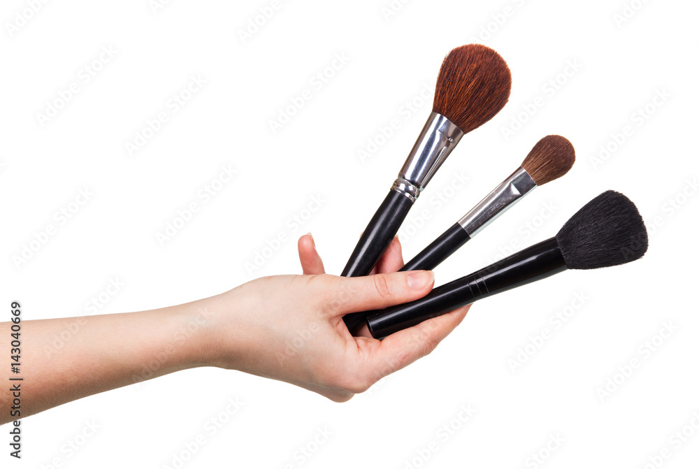 Three cosmetic brushes in female hand close-up isolated on white. Three cosmetic brushes in female hand close-up isolated on white.