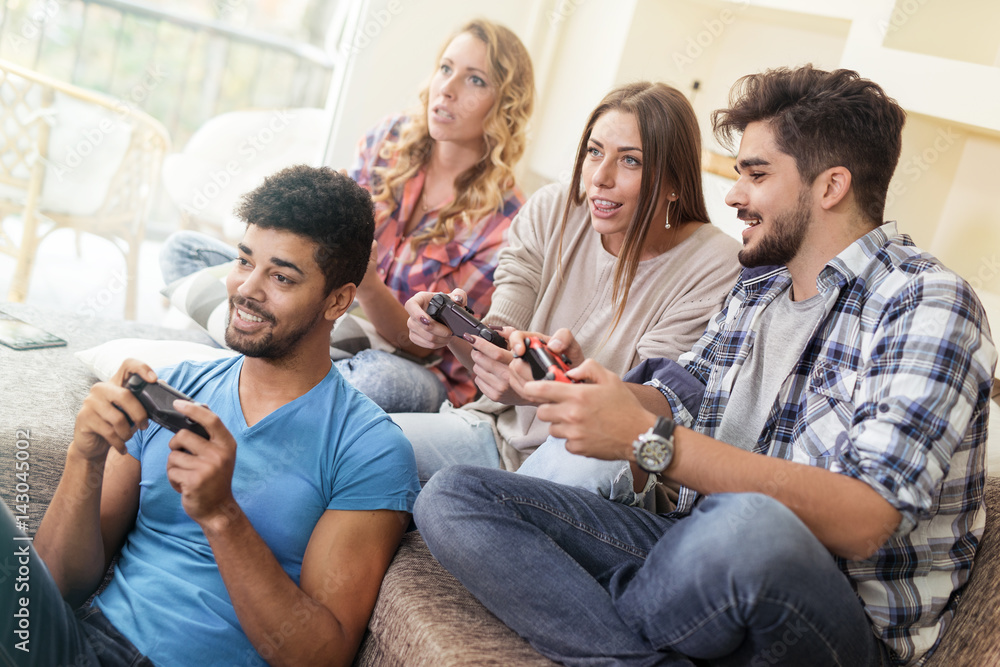 Friends having fun on the couch with video games - obrazy, fototapety, plakaty 