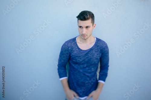 Modischer Mann mit blauem Shirt vor blauer Wand