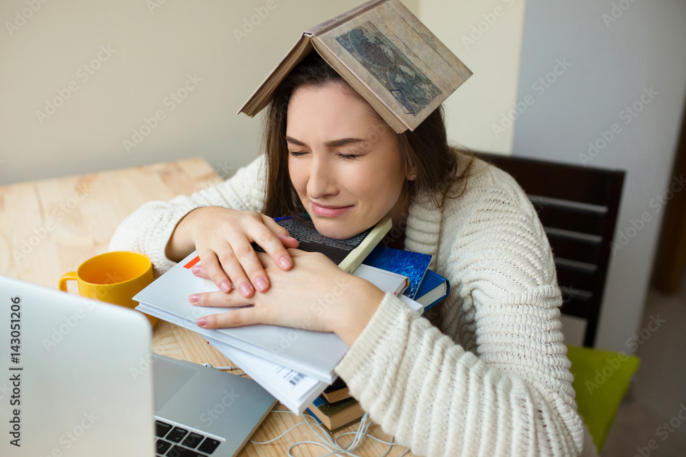 Upset student crying at the desk with lots of books. Girl tired of
