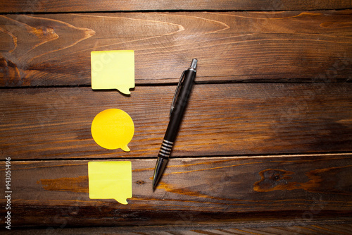 Yellow bright stickers in the form of messages with pen on wooden background. Top view