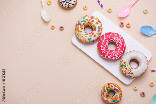 Party. Different colourful sugary round glazed donuts and bottles of drinks on light color background.