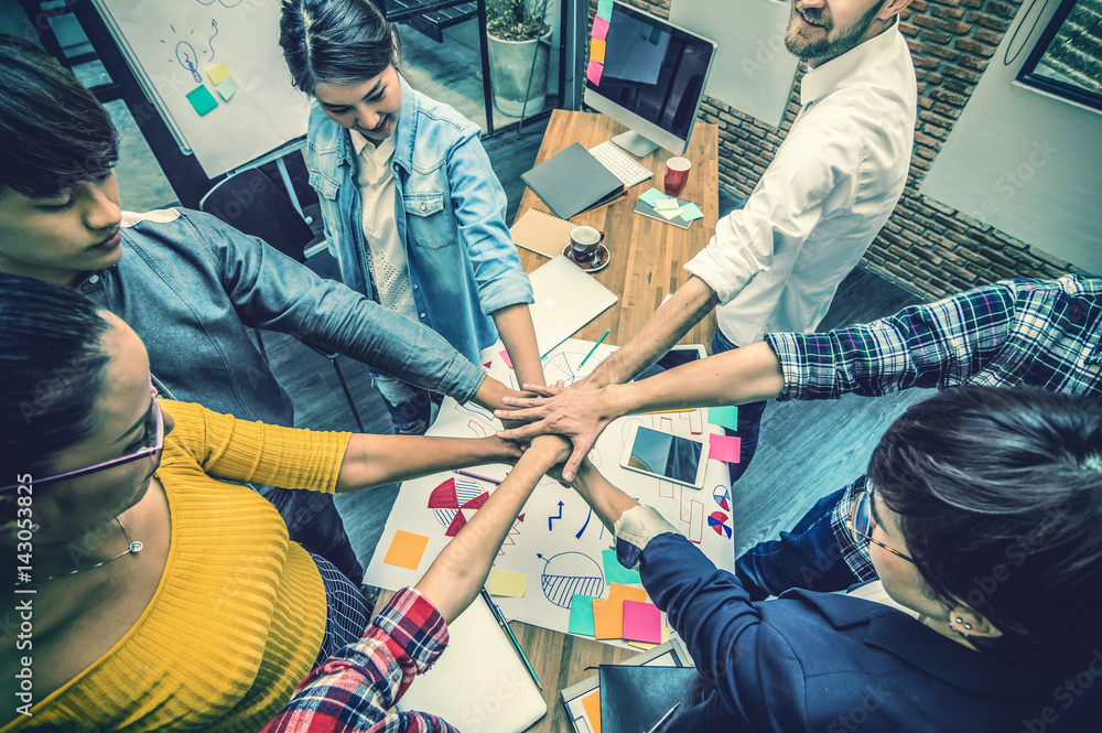 Fototapeta premium Top view of Group Of Asian and Multiethnic Business people making pile of hands in the modern office, people business teamwork group concept