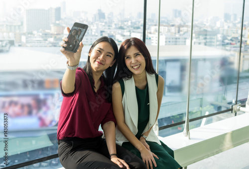 Couple Asian Women using the smartphone do selfie themself In the modern creative Office, business social network concept