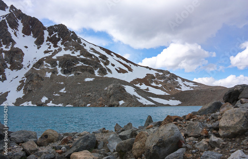 the stony coast of a lagoon at the snow-covered ridge of in Los Glaciares National Park in Argentina