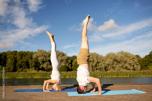 couple making yoga headstand on mat outdoors
