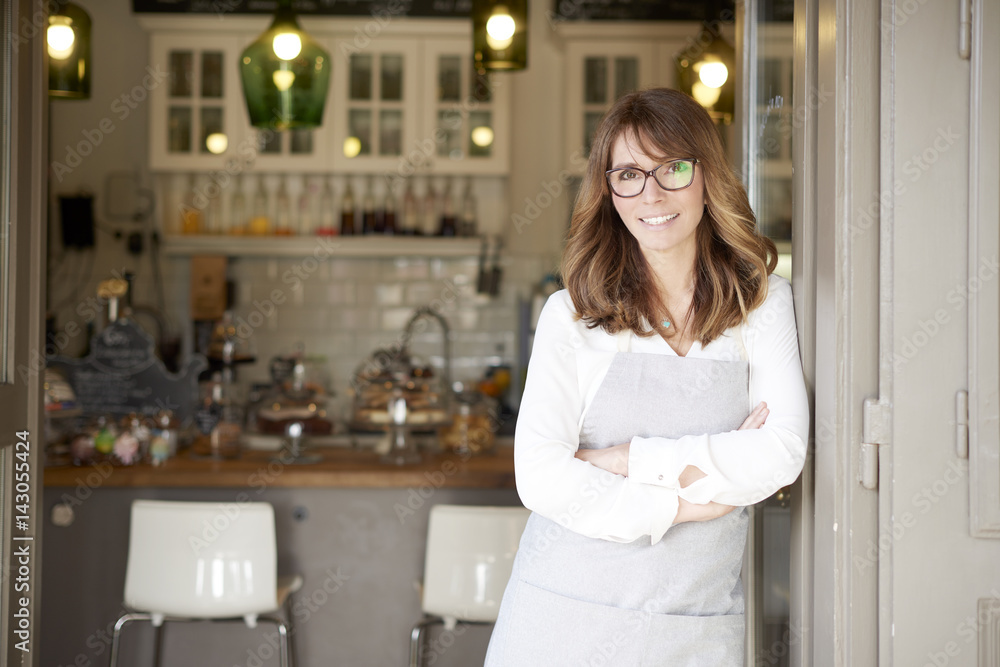 Proud small coffee shop owner businesswoman. Shot of a happy barista woman standing at doorway and inviting to her coffee shop. Small business. Proud small coffee shop owner businesswoman. Shot of a happy barista woman standing at doorway and inviting to her coffee shop. Small business.