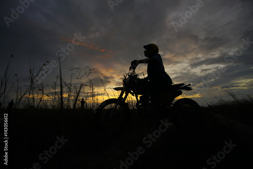 Silhouette of a man riding his motorcycle during sunset.