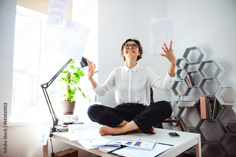 Obraz premium Young beautiful businesswoman throwing up papers, sitting on table.