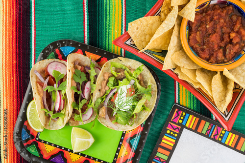Vegetarian corn tacos with refried beans and vegetables.