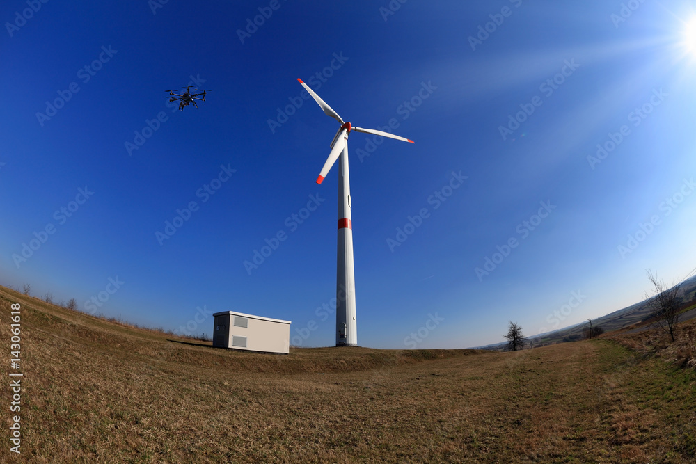 Dron latający nad turbiną wiatrową, promienie słoneczne.