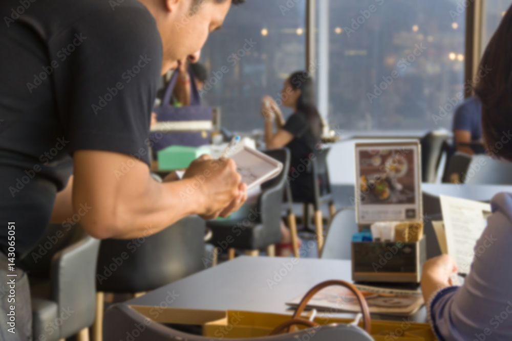 Young man eating food in a restaurant. woman checking his order written by waitress. Young waitress offering tasty dishes to guests. Waitress writing a order.