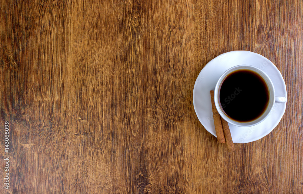 A cup of coffee and cinnamon on a wooden table. View from above. A cup of coffee and cinnamon on a wooden table. View from above.