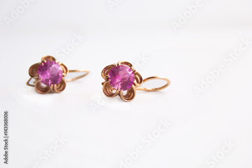 Gold earrings with a pink jewel on a white background. © dvulikaia