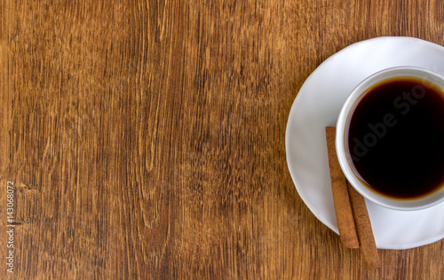 A cup of coffee and cinnamon on a wooden table. View from above.