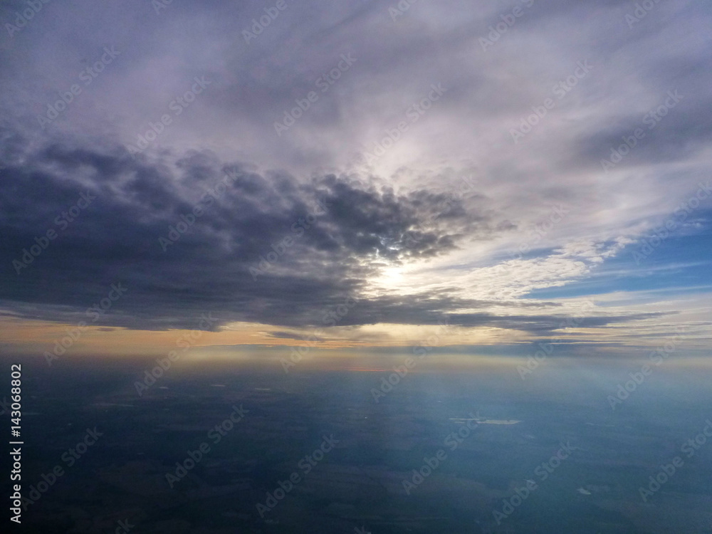 Sun breaking out behind clouds, seen from a plane window