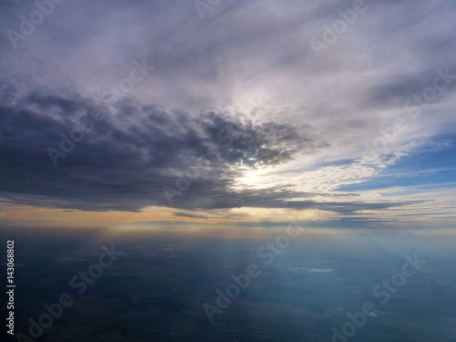 Sun breaking out behind clouds, seen from a plane window