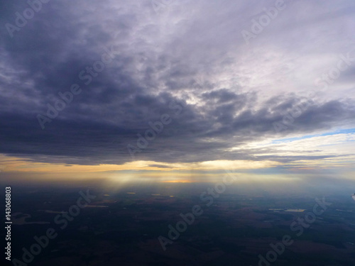 Sun breaking out behind clouds, seen from a plane window