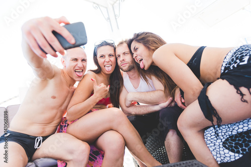 Group of friends millennials using smart phone taking selfie - social network, friendship, having fun concept