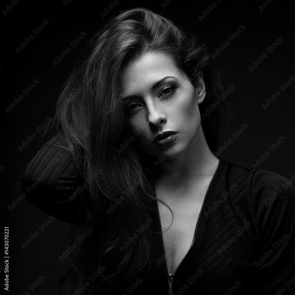 Sexy calm glamour female model with long hair posing in black shirt on dark black background with red lipstick. Black and white art portrait. Vogue