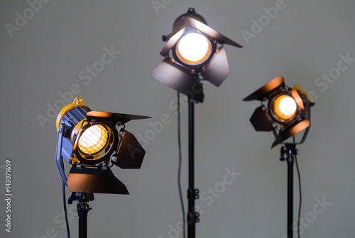 Three halogen spotlights with Fresnel lenses on a grey background. Photographing and filming in the interior. Lighting equipment for movie production.