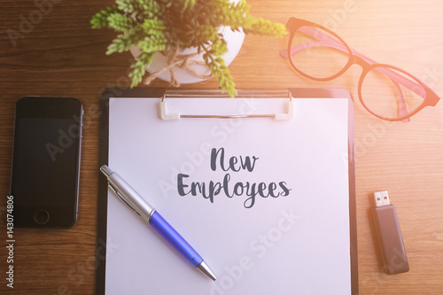 Business concept - Top view notebook writing New Employees.