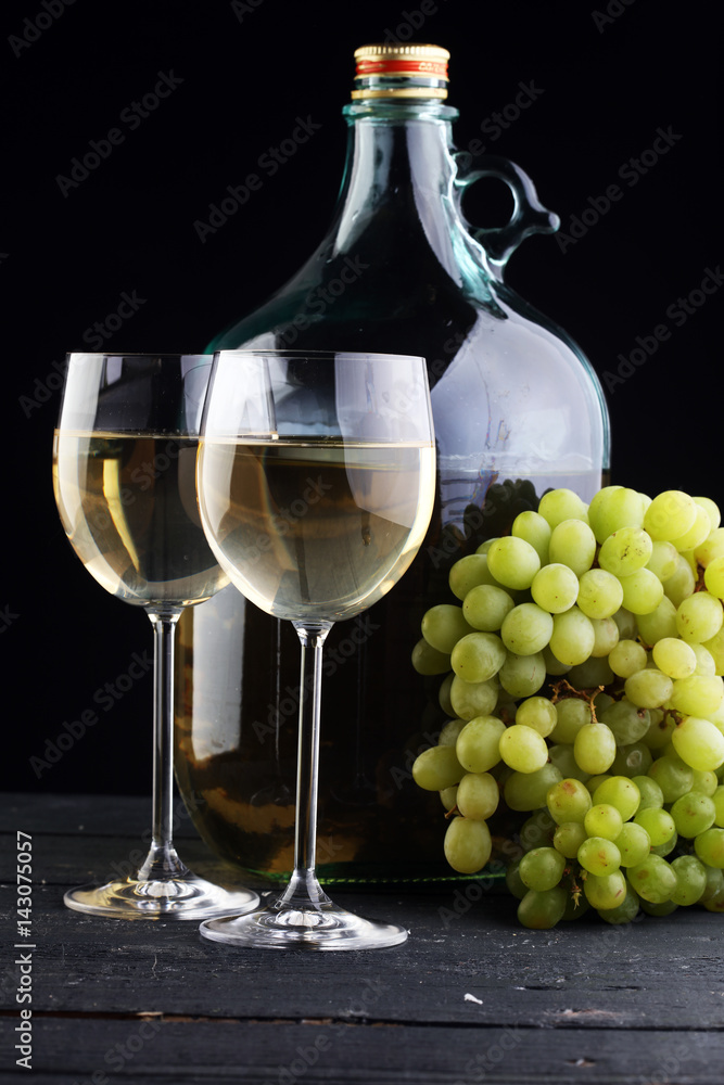 Fototapeta premium Bottle and glass of white wine, grape on wooden table