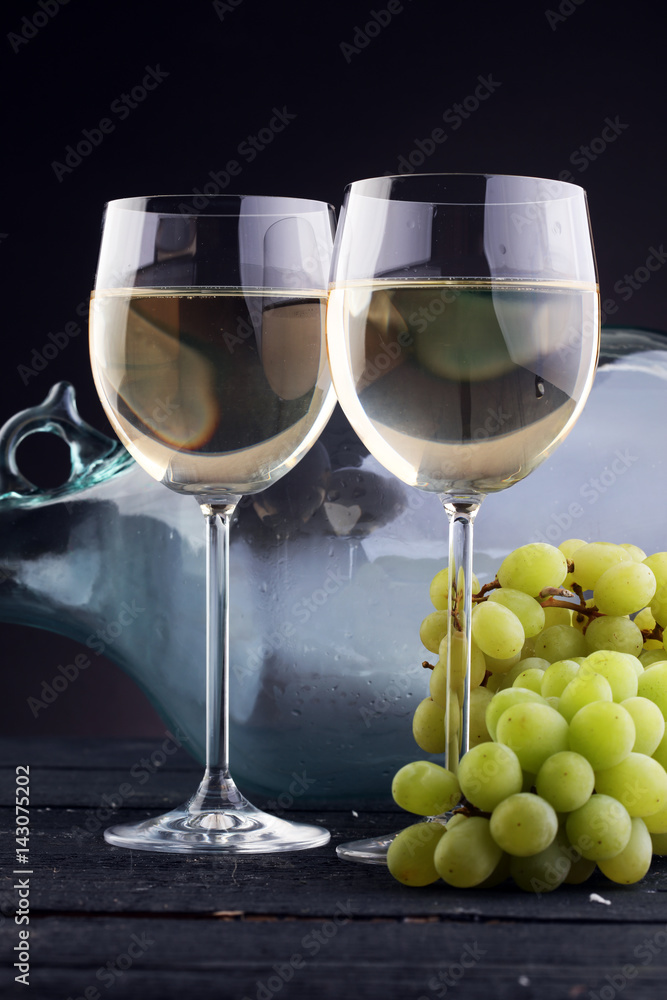 Bottle and glass of white wine, grape on wooden table