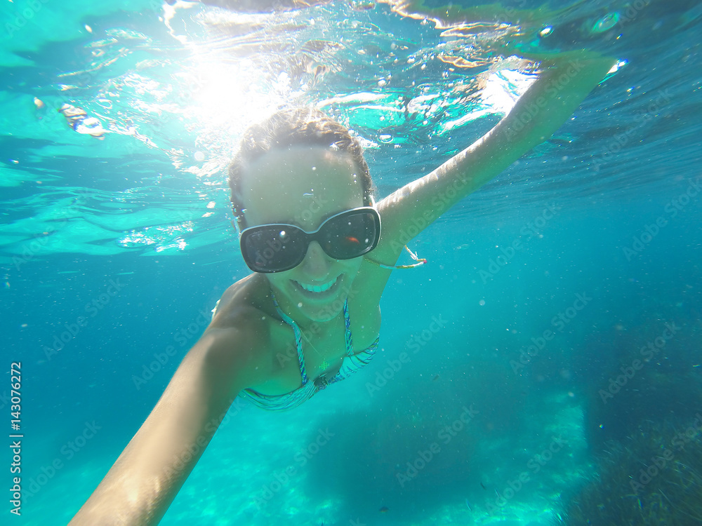 Naklejka premium Underwater shoot of a woman swimming over sandy sea bottom