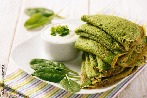 Spinach green pancakes (crepes) with sour cream.