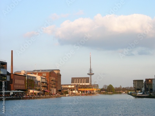 Blick über den Binnenhafen auf den Kreativkai mit Hafenpromenade und dem Fernmeldeturm im Licht der untergehenden Sonne am Hafen in Münster in Westfalen am Dortmund-Ems-Kanal im Münsterland photo