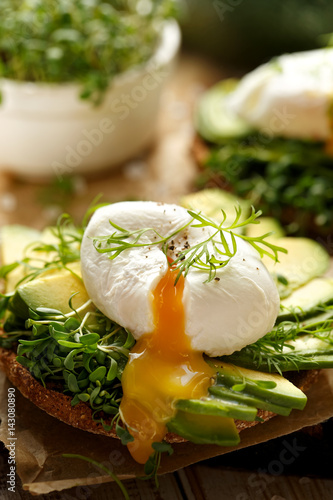 Sandwich with avocado and poached egg with addition of fresh herbs