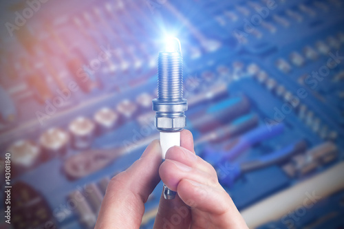 Mechanic holds a spare part spark plug in his hand. Auto part spark plug close-up.