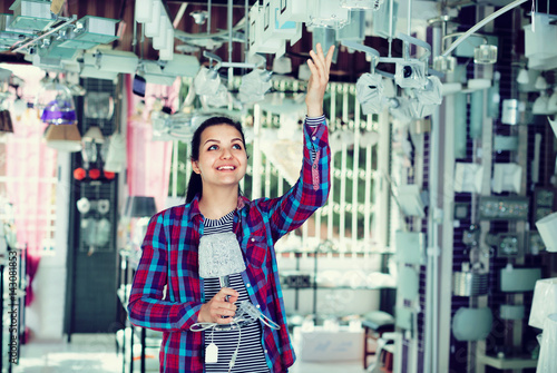 Girl in lighter shop chooses stylish and modern chandelier lamp