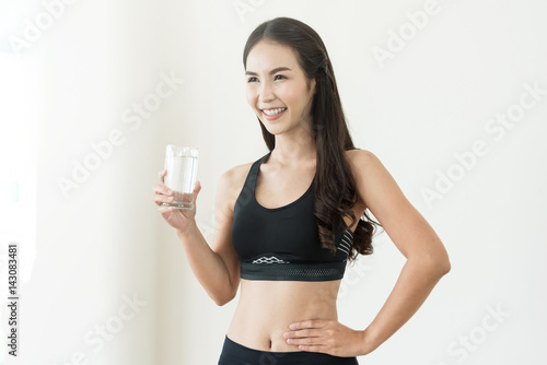 Happiness Young Asian Woman in black sportswear holding glass of water on white isolated background. Healthy, Diet, Beauty, smiling. © eggeeggjiew