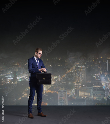 Businessman with briefcase standing on a night city background.  Job  business  career  concept.