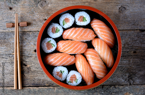 Homemade sushi with fresh salmon and cucumber on old wooden background. 