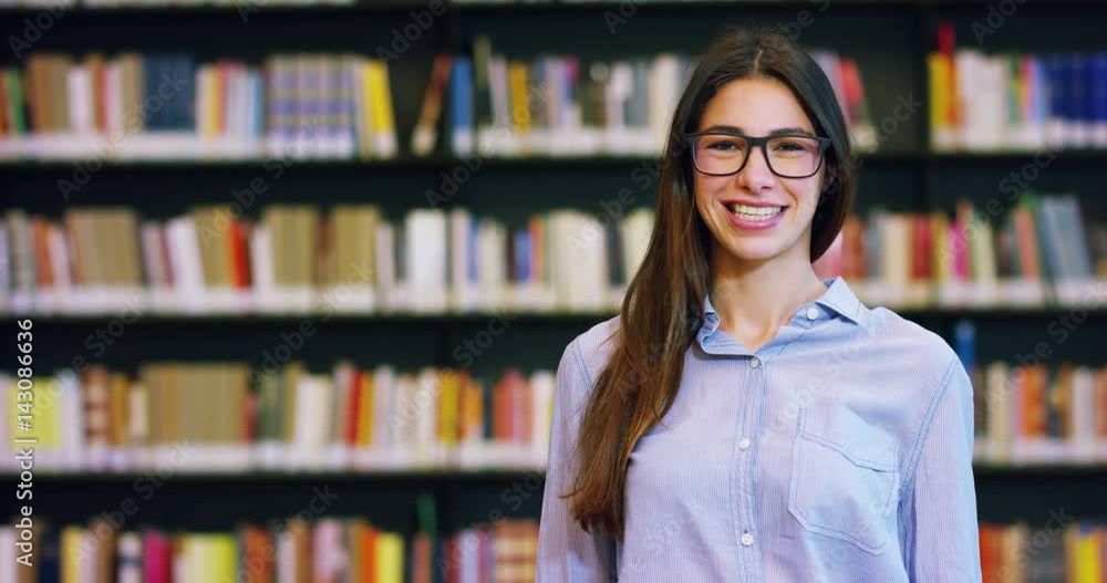 Portrait of a beautiful young woman smiling happy in a library holding books after doing a search and after studying. Concept: educational, portrait, library, and studious. Portrait of a beautiful young woman smiling happy in a library holding books after doing a search and after studying. Concept: educational, portrait, library, and studious.