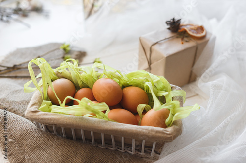 Close-up rustic basket with eggs in composition with gift box and veil.