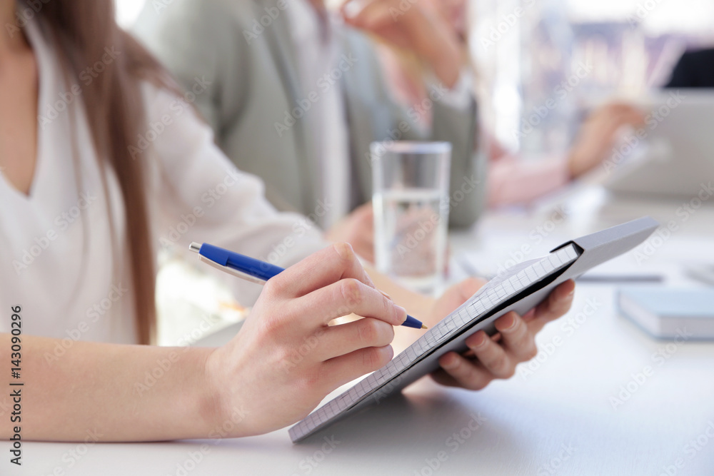 Fototapeta premium Woman making notes in notebook at business presentation