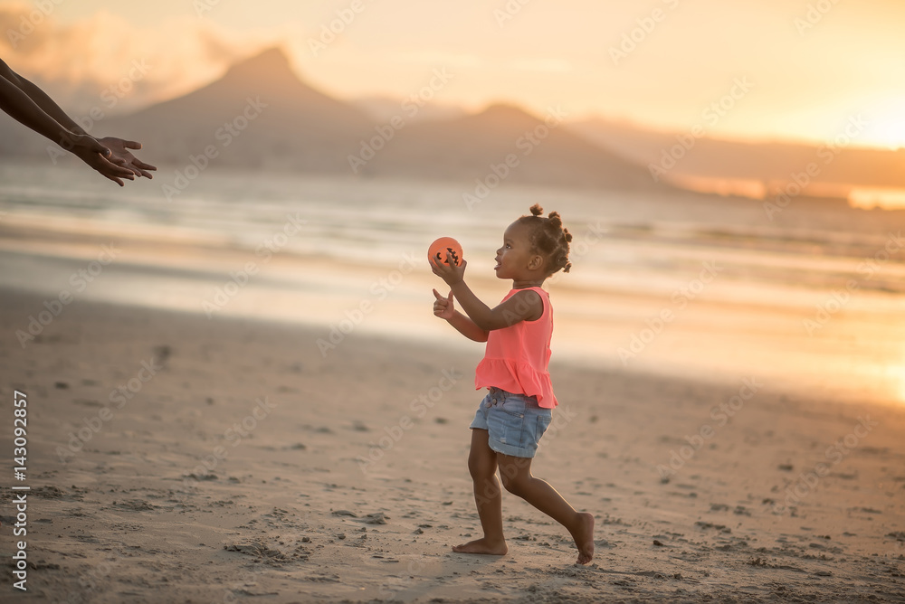 Little girl holding ball at the beach at sunset Little girl holding ball at the beach at sunset